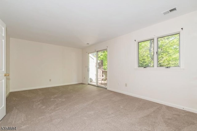 carpeted spare room with visible vents and baseboards