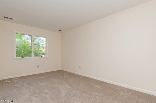 spare room featuring light colored carpet, baseboards, and visible vents