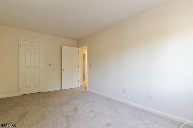 spare room with baseboards and light carpet