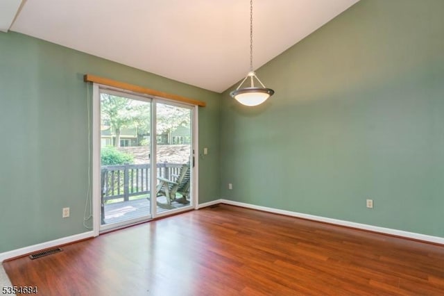 empty room with baseboards, visible vents, wood finished floors, and lofted ceiling