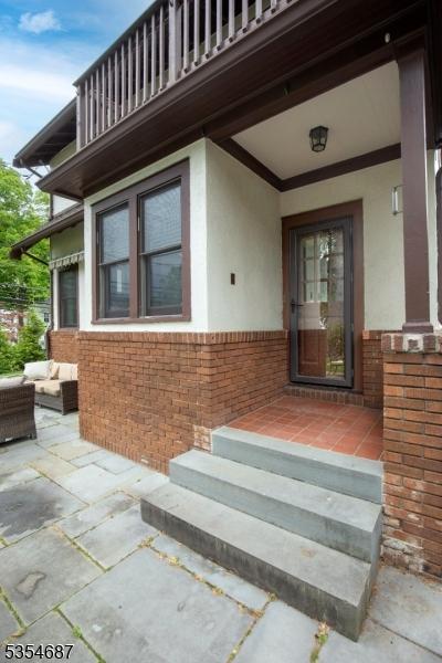 1 Ambar Pl, Bernardsville Boro, NJ 07924 - doorway to property with a balcony, stucco siding, brick siding, and an outdoor living space