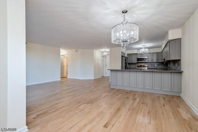 kitchen with open floor plan, appliances with stainless steel finishes, a chandelier, and gray cabinets