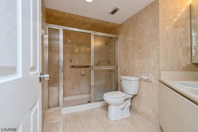 bathroom with visible vents, tile walls, a shower stall, tile patterned floors, and toilet