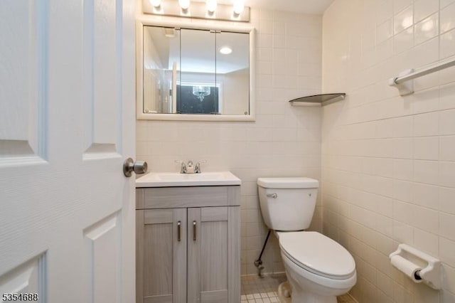 half bathroom with tile walls, vanity, and toilet
