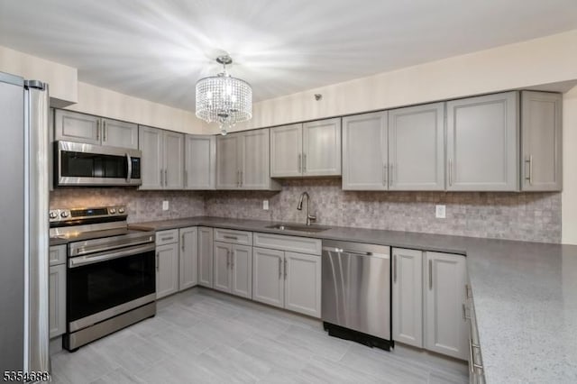 kitchen with a chandelier, appliances with stainless steel finishes, decorative backsplash, and a sink