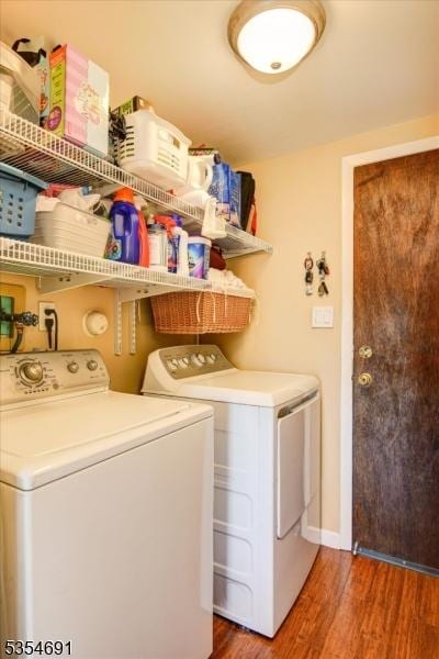 clothes washing area featuring laundry area, washing machine and dryer, and wood finished floors