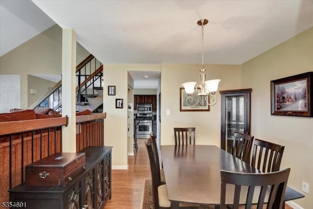 dining space featuring baseboards, an inviting chandelier, stairway, and light wood-style floors