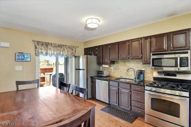 kitchen with a sink, tasteful backsplash, stainless steel appliances, and dark brown cabinets