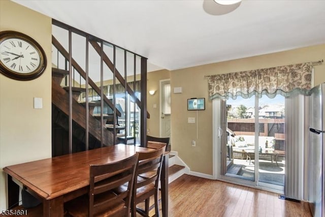 dining space with baseboards, wood finished floors, and stairway