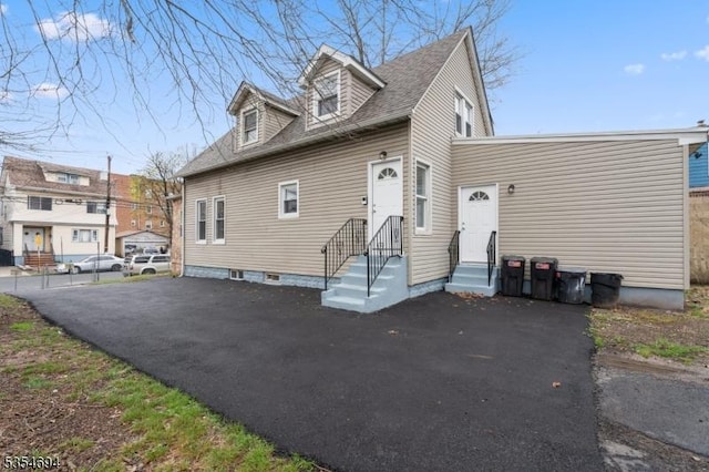 new england style home featuring entry steps and roof with shingles