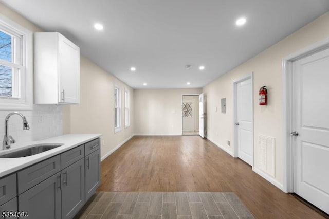 kitchen with a sink, gray cabinets, recessed lighting, light countertops, and baseboards