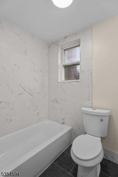 full bathroom with toilet and tile patterned flooring