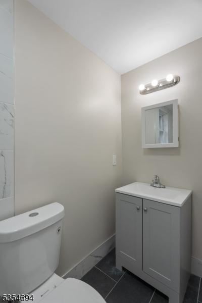 bathroom featuring toilet, marble finish floor, baseboards, and vanity