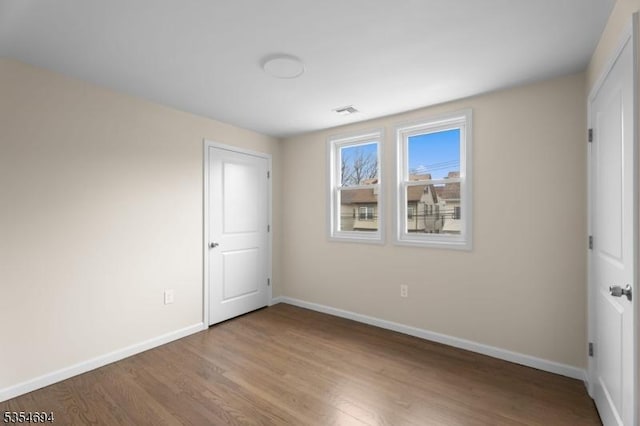 unfurnished bedroom featuring baseboards, visible vents, and wood finished floors