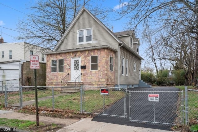 bungalow-style home featuring stone siding, a fenced front yard, a gate, and entry steps