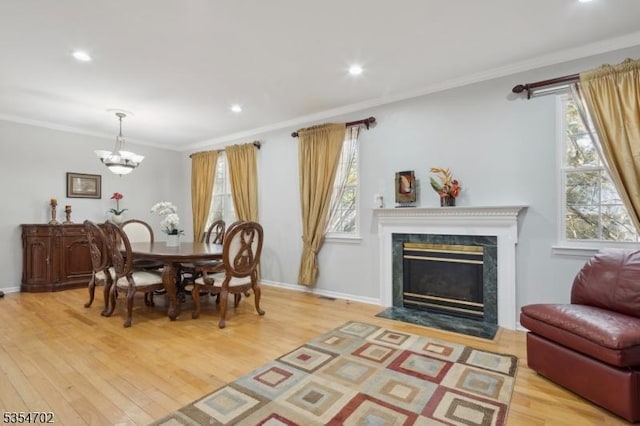dining space with crown molding, a chandelier, wood finished floors, and a fireplace