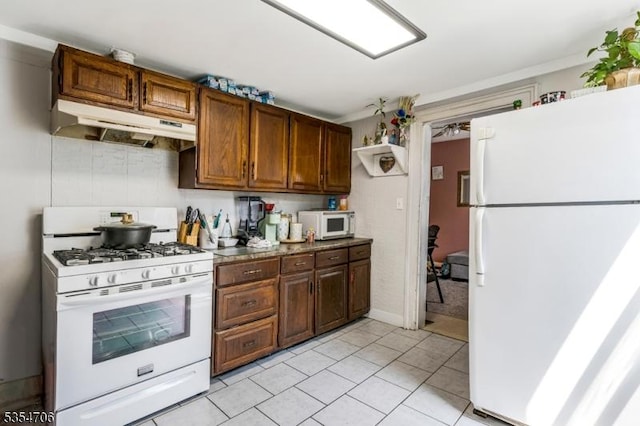 kitchen featuring white appliances, under cabinet range hood, and light tile patterned floors