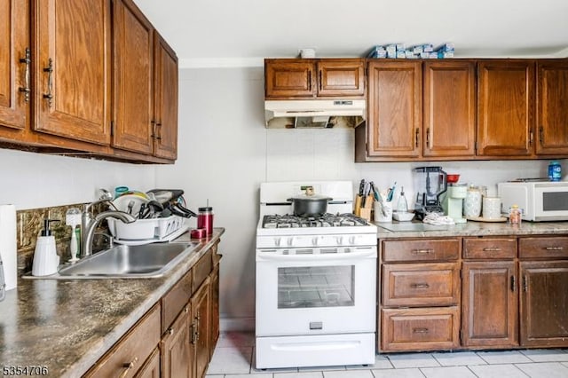 kitchen featuring under cabinet range hood, white appliances, a sink, and light tile patterned floors