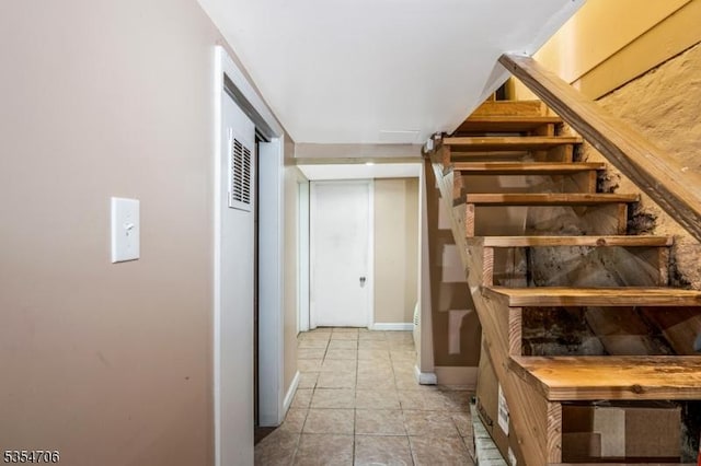 stairway featuring baseboards and a heating unit