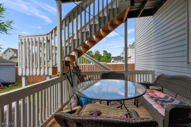 wooden terrace with outdoor dining space and stairs