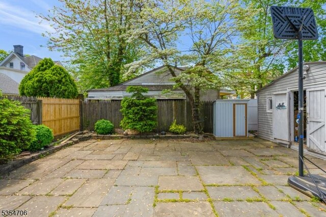 view of patio with a fenced backyard, an outbuilding, and a storage unit