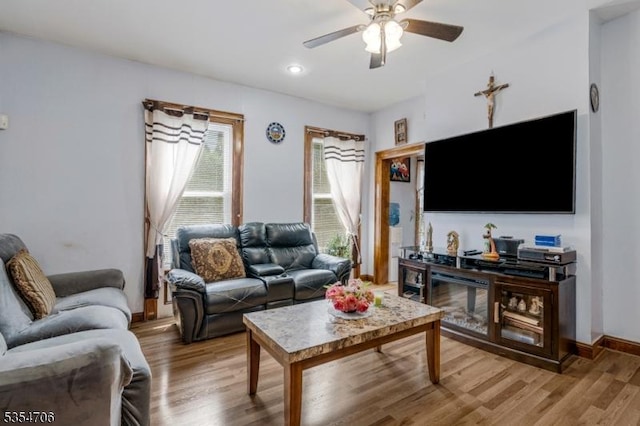 living room featuring ceiling fan, light wood-style floors, and baseboards