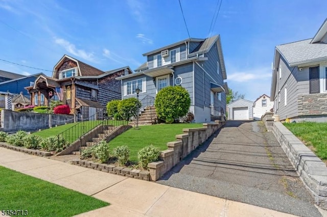 view of front of home featuring driveway, a residential view, an outbuilding, a detached garage, and a front lawn