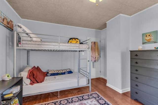 bedroom with baseboards, ornamental molding, and wood finished floors