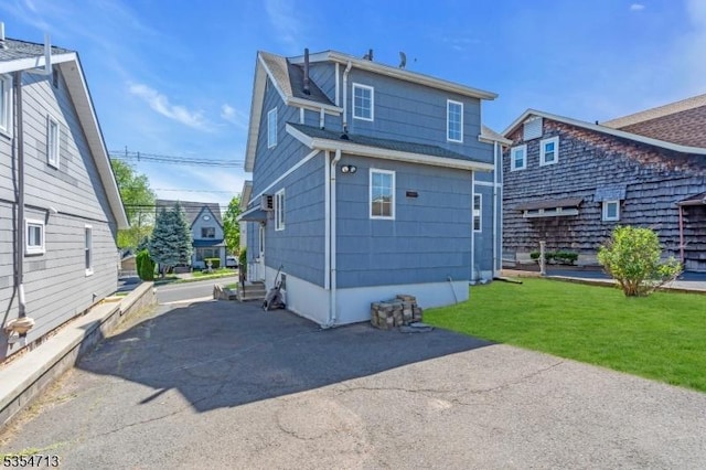 rear view of property featuring a lawn and entry steps