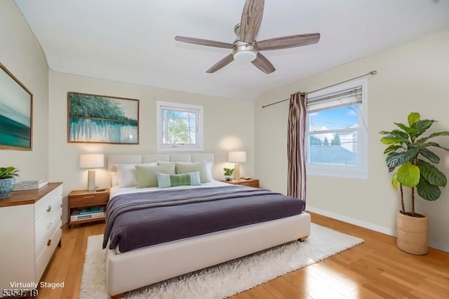 bedroom featuring baseboards, multiple windows, ceiling fan, and light wood-style floors