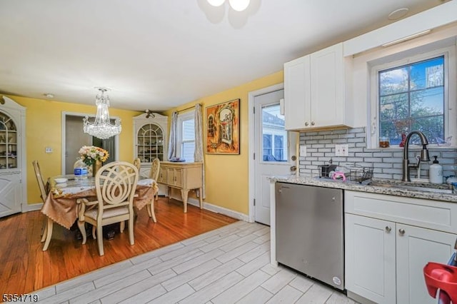 kitchen with a sink, a chandelier, light wood-style flooring, baseboards, and stainless steel dishwasher