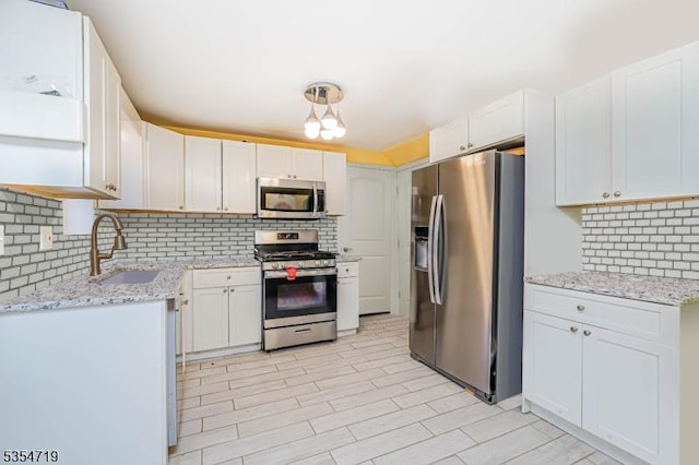 kitchen with a sink, white cabinets, tasteful backsplash, and stainless steel appliances