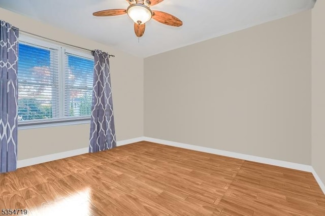 spare room featuring baseboards, a ceiling fan, and light wood-type flooring