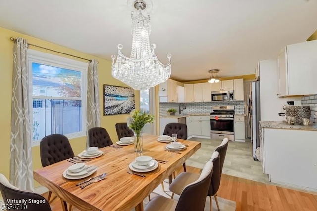 dining space with light wood finished floors and a chandelier