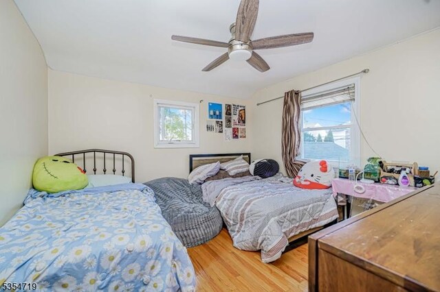 bedroom featuring ceiling fan, multiple windows, and light wood-type flooring