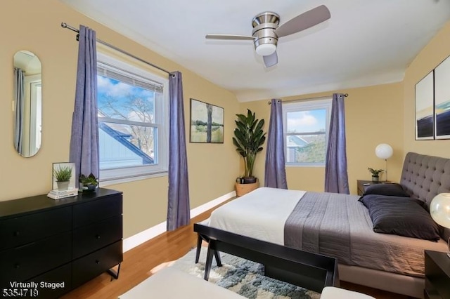 bedroom with light wood-style floors, baseboards, ceiling fan, and multiple windows