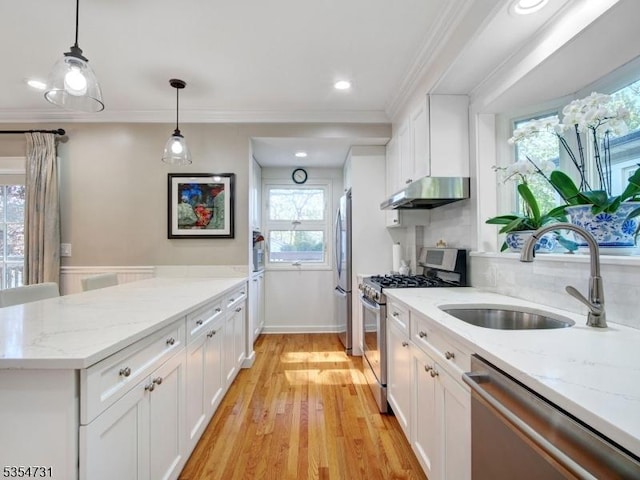 kitchen featuring appliances with stainless steel finishes, a sink, white cabinets, a peninsula, and under cabinet range hood