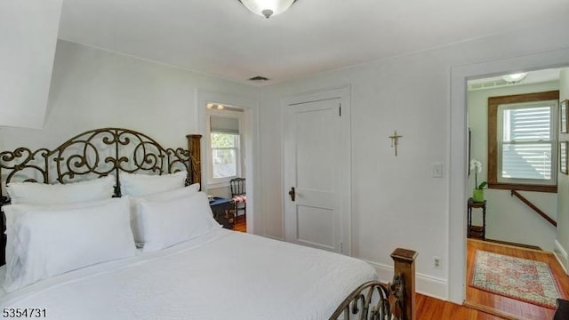 bedroom featuring baseboards, visible vents, wood finished floors, and a closet