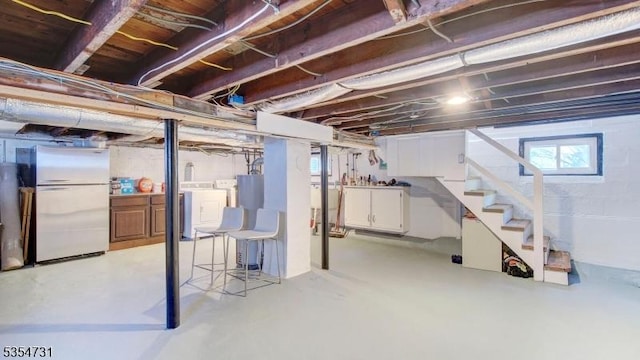 below grade area with freestanding refrigerator, stairs, plenty of natural light, and washer and clothes dryer