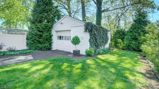 detached garage featuring fence and driveway