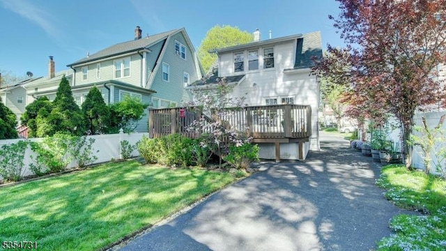 view of front of home with fence, a chimney, a deck, and a front yard