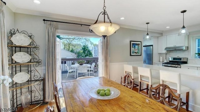 dining room with crown molding, recessed lighting, wood finished floors, and a wainscoted wall