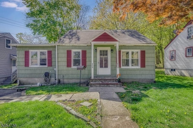 bungalow-style house with roof with shingles and a front yard