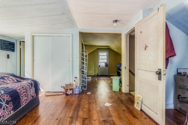 bedroom with radiator, a closet, hardwood / wood-style flooring, and lofted ceiling