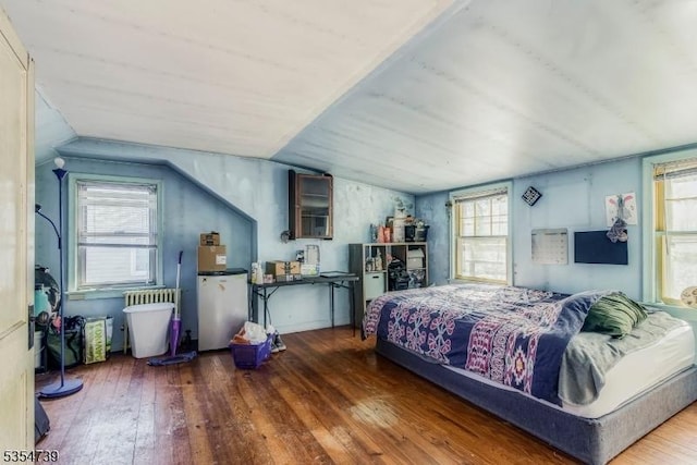 bedroom with refrigerator, multiple windows, lofted ceiling, and hardwood / wood-style floors