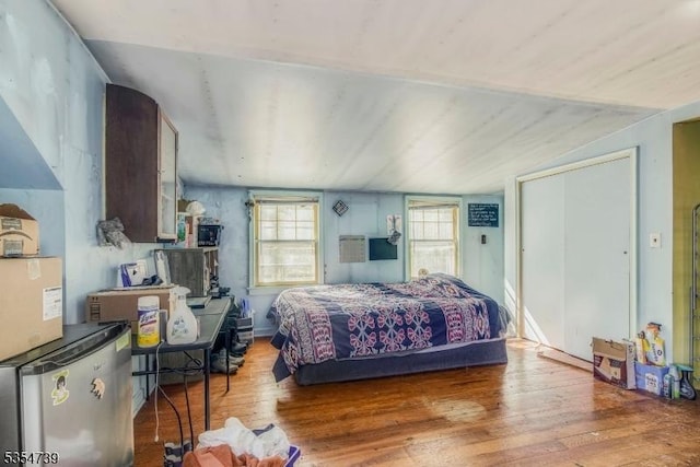 bedroom featuring fridge, hardwood / wood-style flooring, and lofted ceiling