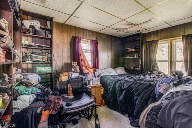 bedroom with carpet flooring, wood walls, and a paneled ceiling