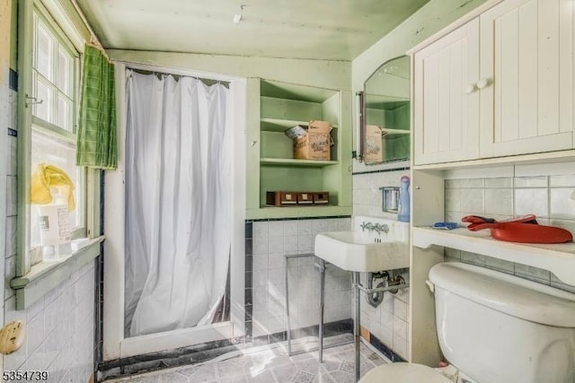 bathroom featuring toilet, tile walls, and curtained shower