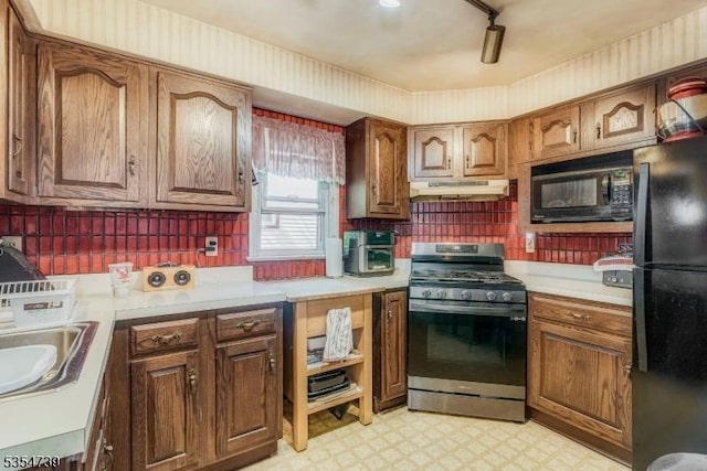 kitchen with light countertops, light floors, black appliances, and under cabinet range hood
