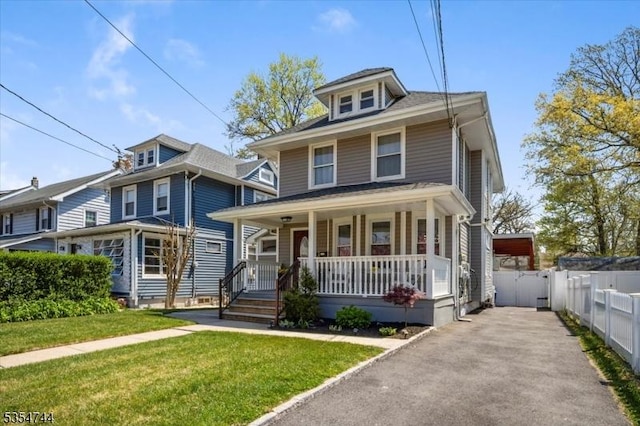 american foursquare style home with fence, covered porch, and a front lawn